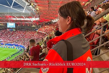 Einsatzkraft des DRK steht auf einer Tribüne im Stadion